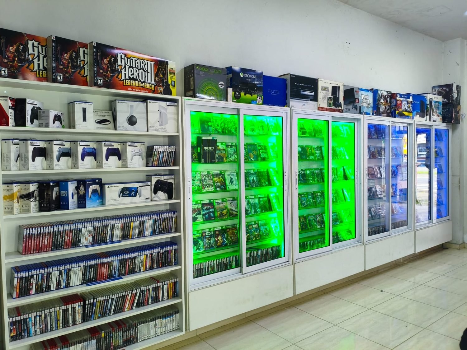 Prateleiras e vitrines com jogos de PS4, PS5, Xbox 360 e Xbox One na loja Impakto Games em Caraguatatuba