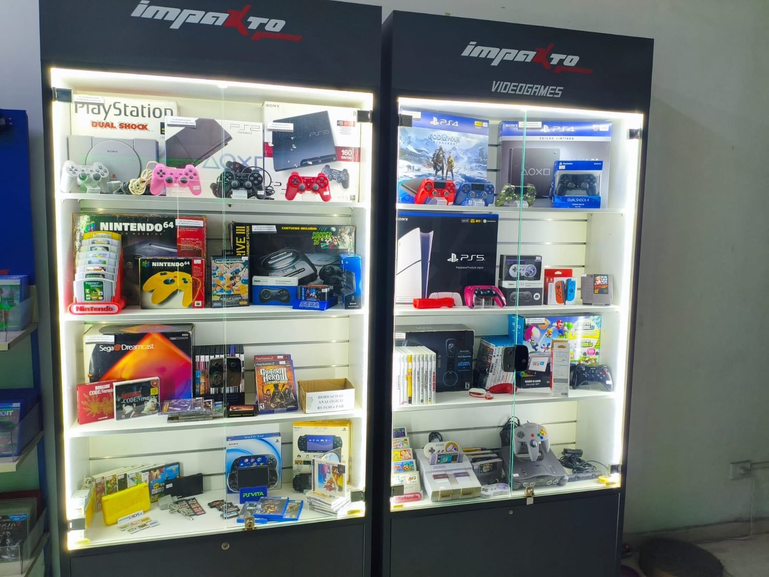 Vitrine com consoles retrô e colecionáveis: PS1, PS2, Nintendo 64, Super Nintendo, Mega Drive e Dreamcast na Impakto Games